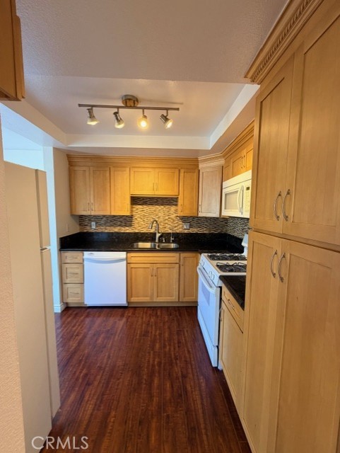 2500 East 4th Street, Unit 203 Long Beach, CA 90814 - Photo 11 of 35 a kitchen with granite countertop a refrigerator and wooden floor