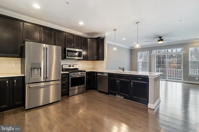 a large kitchen with a large counter top stainless steel appliances and wooden floor