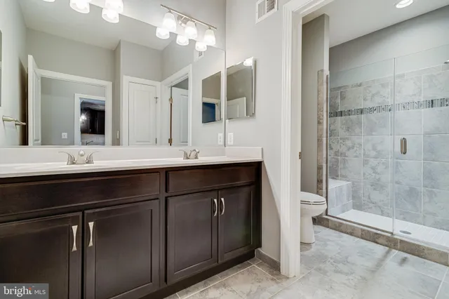 a bathroom with a double vanity sink mirror and toilet