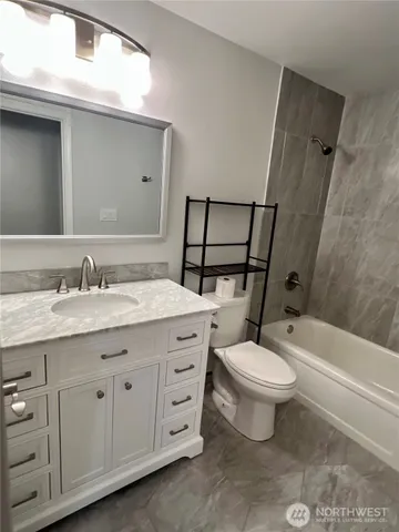 a bathroom with a granite countertop toilet a sink and a bathtub