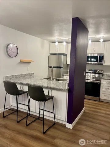 a kitchen with kitchen island granite countertop a sink cabinets and stainless steel appliances