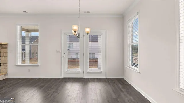 a view of an empty room with wooden floor and a ceiling fan