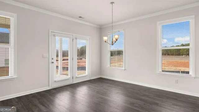 a view of an empty room with window and kitchen view