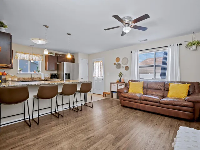 a living room with couches and kitchen view with wooden floor