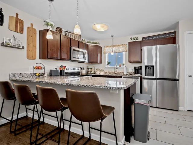 a kitchen with stainless steel appliances granite countertop a sink a stove a refrigerator and cabinets