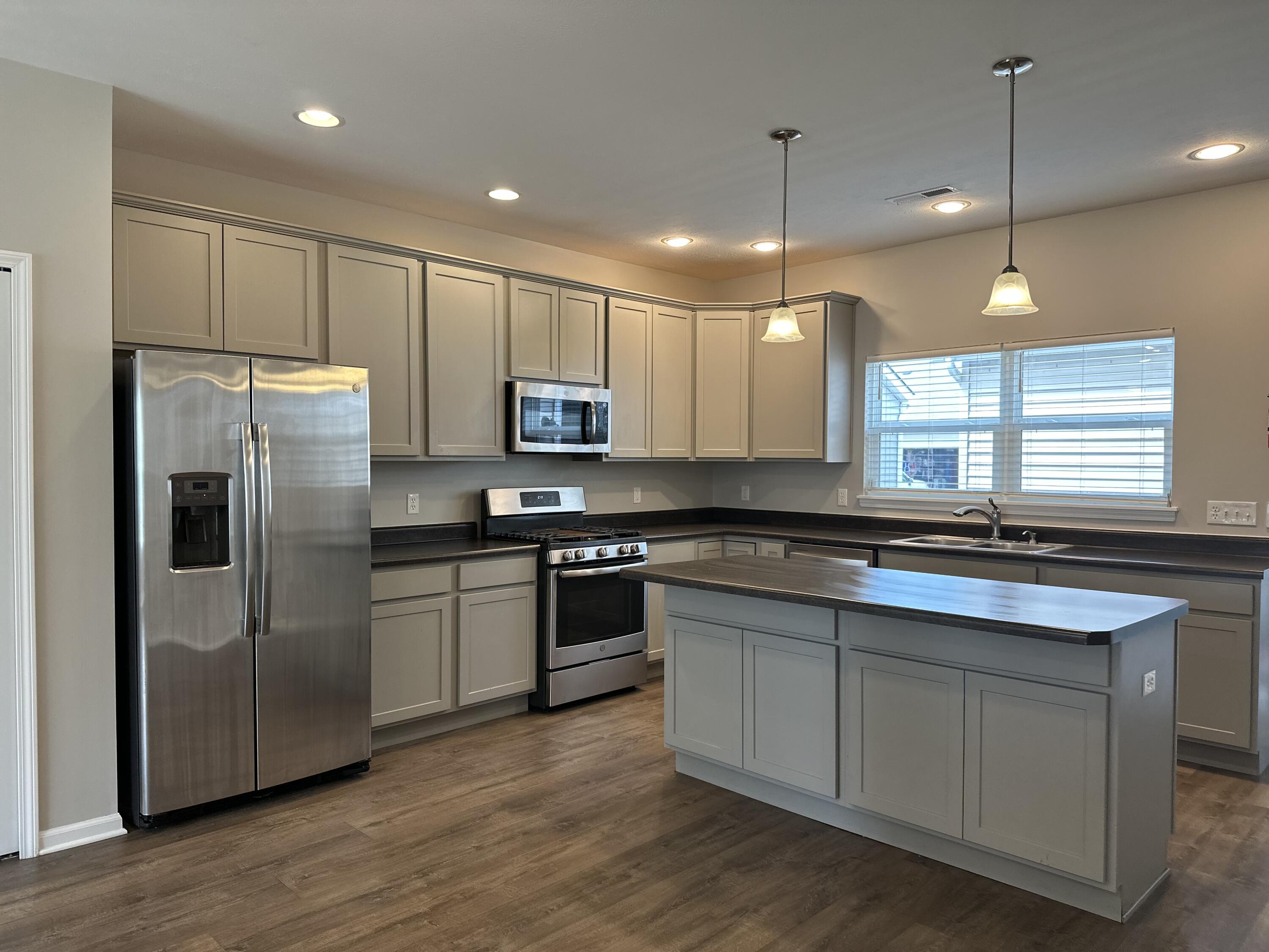 1077 East 115th Lane Crown Point, IN 46307 - Photo 4 of 16 a kitchen with stainless steel appliances granite countertop a sink a stove a refrigerator and island with wooden floor