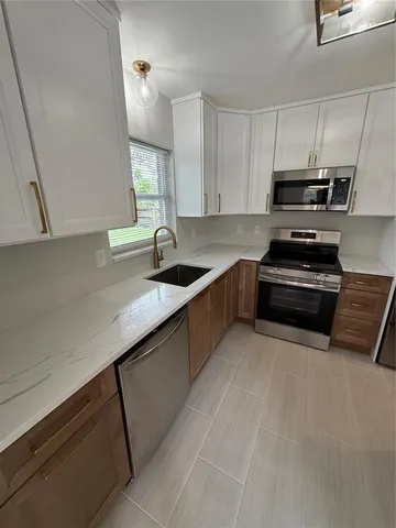 a kitchen with kitchen island stainless steel appliances a sink a stove and a refrigerator