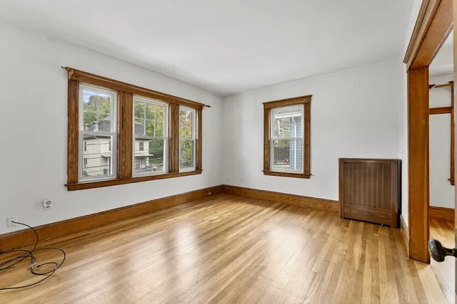 a view of an empty room with a window and wooden floor
