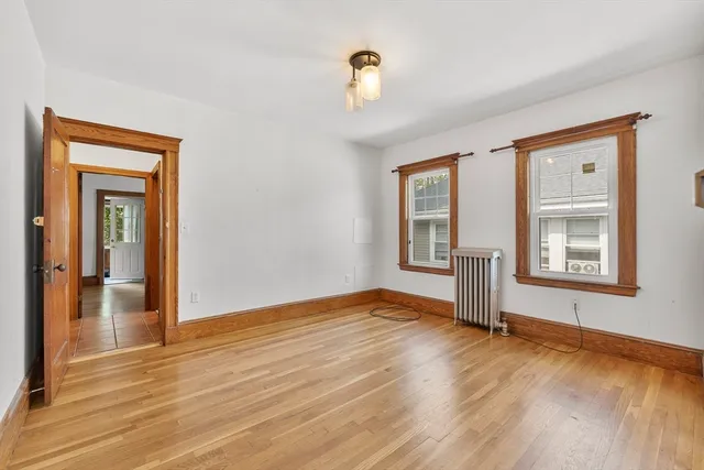 a view of an empty room with window and wooden floor