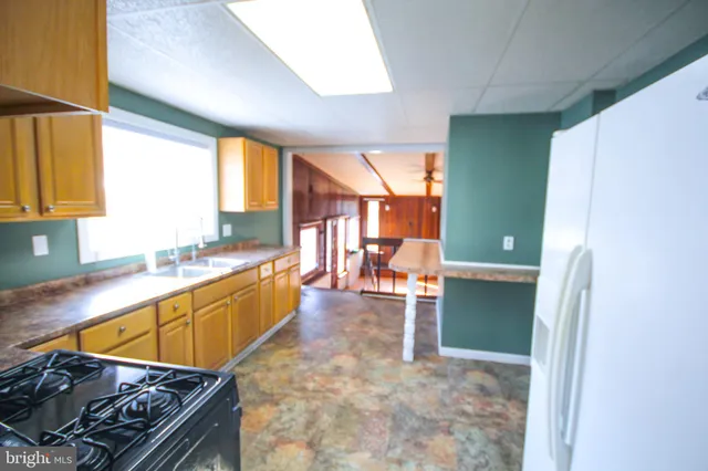 a view of a kitchen with kitchen island granite countertop a refrigerator and a sink