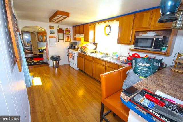 a living room with stainless steel appliances kitchen island granite countertop furniture and a wooden floor
