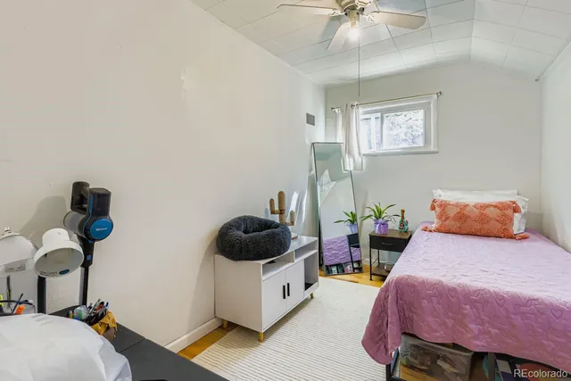a bedroom with a bed table chair and a potted plant