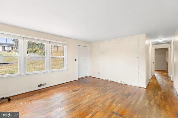 an empty room with wooden floor and windows
