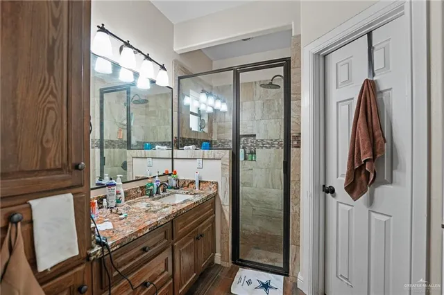a bathroom with a granite countertop sink a mirror and shower