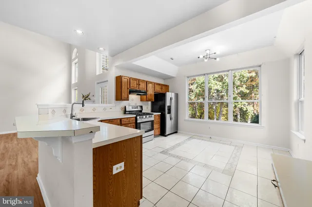 a large white kitchen with a large window appliances and cabinets