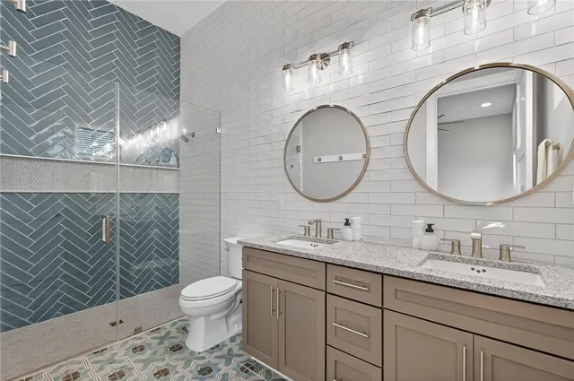 a bathroom with a toilet a double vanity sink and a mirror