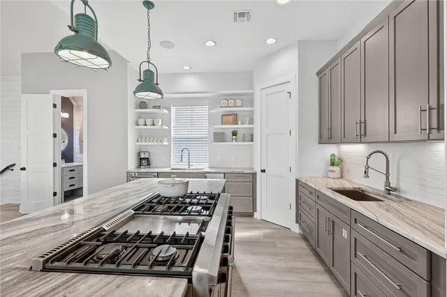 a kitchen with stainless steel appliances granite countertop a stove a sink dishwasher and a refrigerator with wooden cabinets