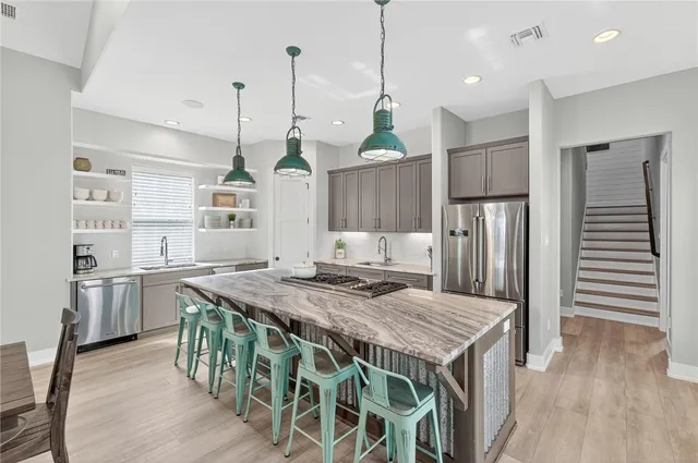 a kitchen with stainless steel appliances granite countertop a kitchen island and a refrigerator