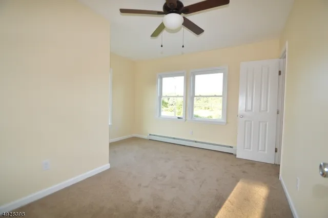 an empty room with windows and fan