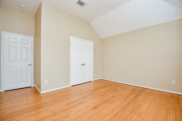 an empty room with wooden floor fan and windows