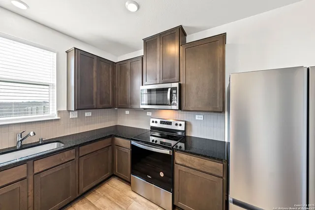a kitchen with stainless steel appliances granite countertop a refrigerator and a sink