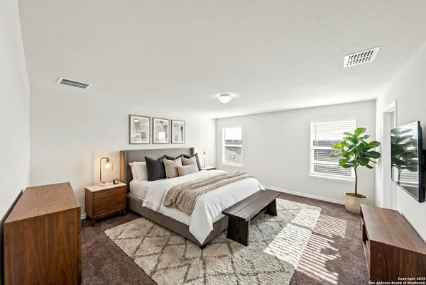 a bedroom with a large bed and a potted plant