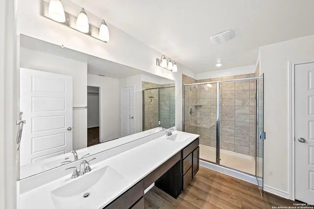 a bathroom with a double vanity sink mirror and shower