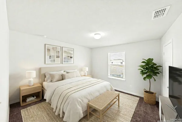 a bedroom with a large bed and a potted plant