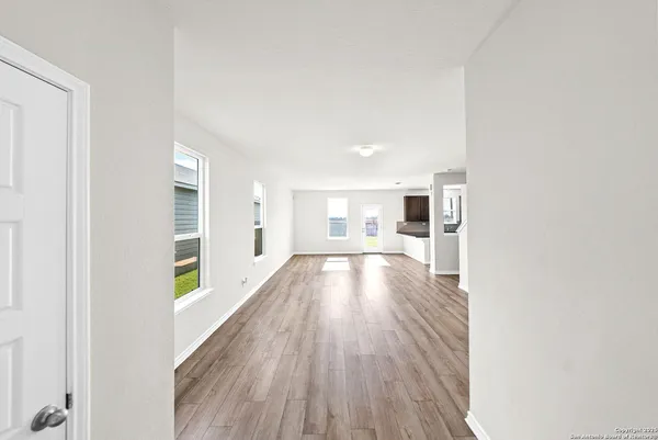 a view of a hallway with wooden floor kitchen and living room