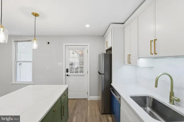 a kitchen with stainless steel appliances kitchen island a refrigerator sink and cabinets