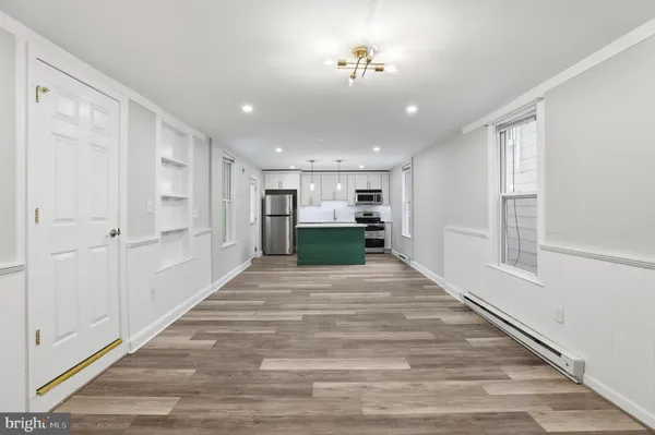 a view of a hallway with wooden floor and a kitchen
