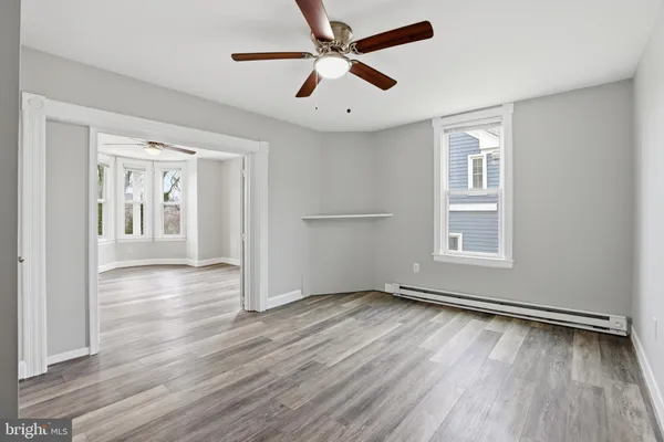 an empty room with wooden floor a ceiling fan and windows
