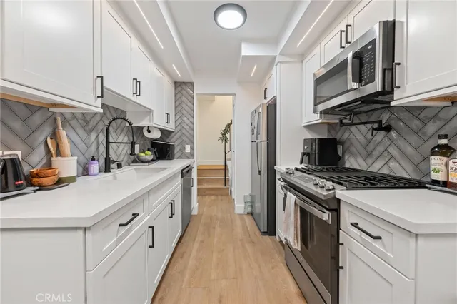 a kitchen with stainless steel appliances a sink stove top oven and cabinets