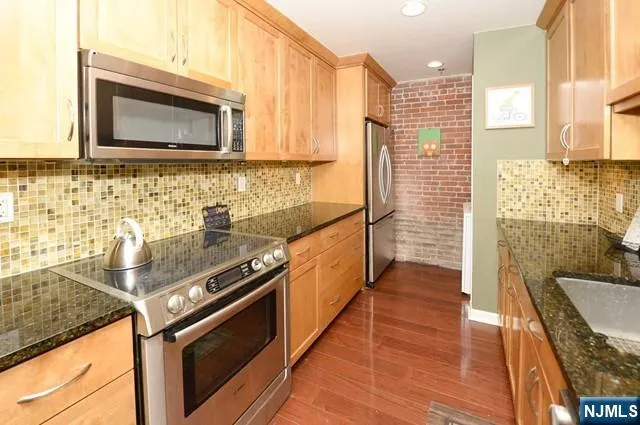 a kitchen with stainless steel appliances granite countertop a stove a sink and a microwave