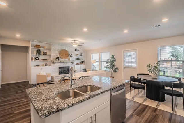 a kitchen with a sink a counter top space and living room view