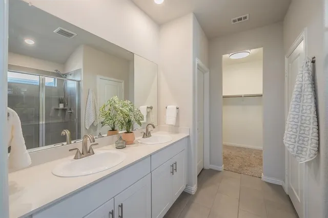 a bathroom with a double vanity sink mirror and shower