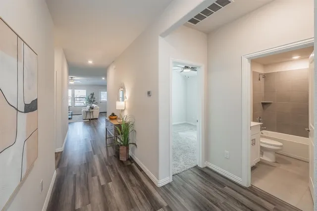 a view of a hallway with wooden floor and a bathroom