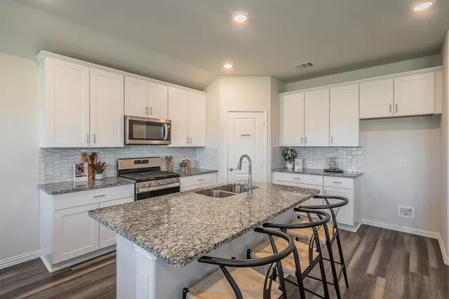 a kitchen with sink a microwave and cabinets