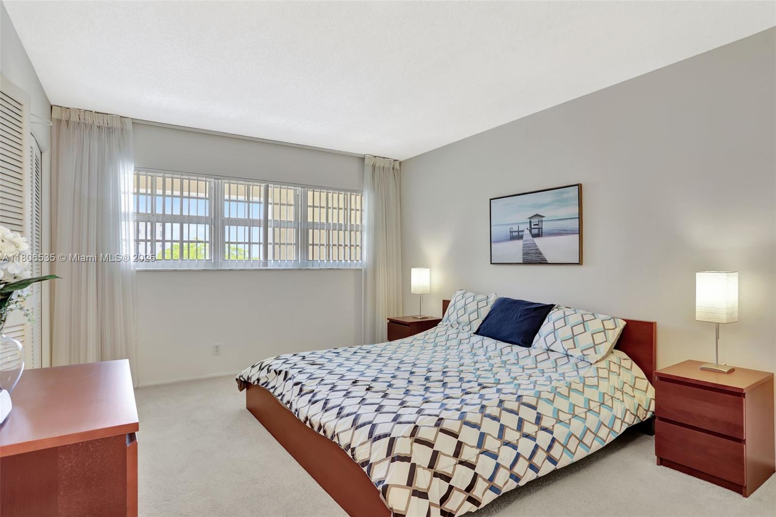 3091 North Course Drive, Unit 502 Pompano Beach, FL 33069 - Photo 20 of 42 a bedroom with a large bed and a lamp