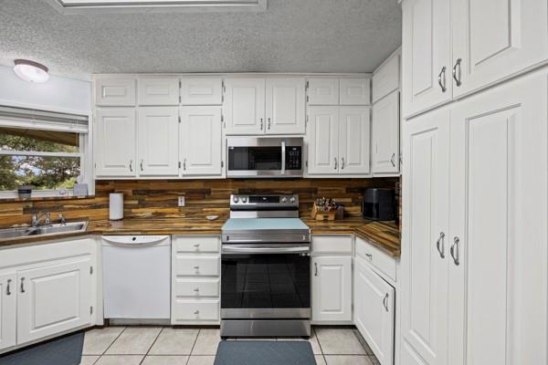 1816 Caddo Peak Road Joshua, TX 76058 - Photo 6 of 38 a kitchen with white cabinets and stainless steel appliances