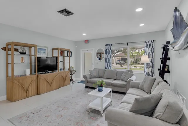 a living room with couches painting on the wall and a large window