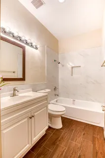 a bathroom with a double vanity sink a toilet and bathtub