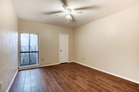 an empty room with wooden floor chandelier fan and windows