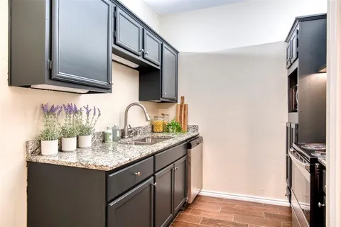 a kitchen with granite countertop a sink stainless steel appliances and cabinets