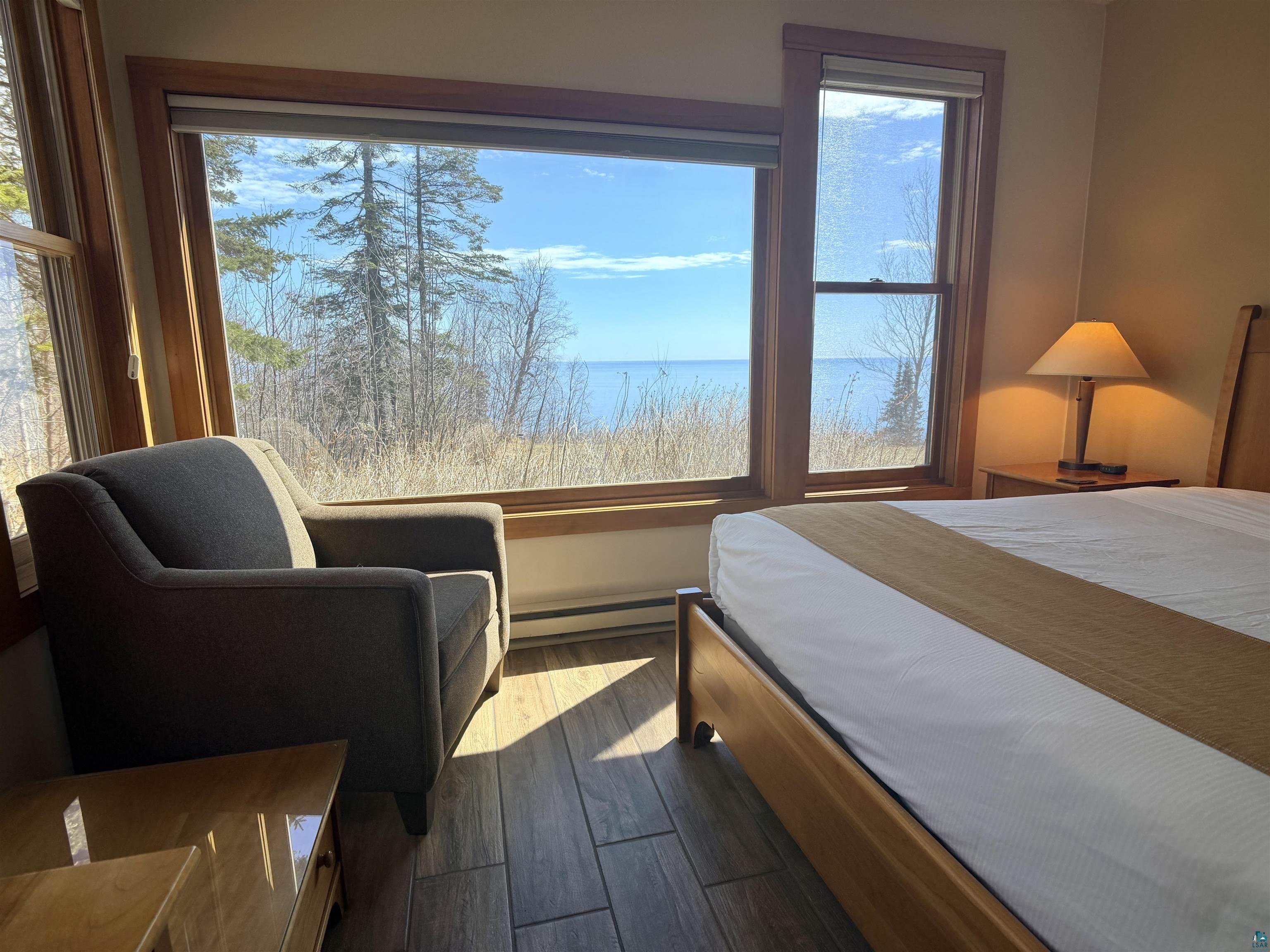 504-506 Poplar River Road, Unit 505 Lutsen, MN 55612 - Photo 36 of 39 Expansive windows showcasing water scenery, complemented by wood-finish flooring, natural wood window trim, and baseboard heating