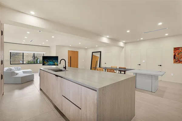 a large kitchen with kitchen island a white counter top space a sink a stove and a refrigerator