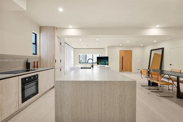 a view of a kitchen with kitchen island a counter top space a sink and stainless steel appliances
