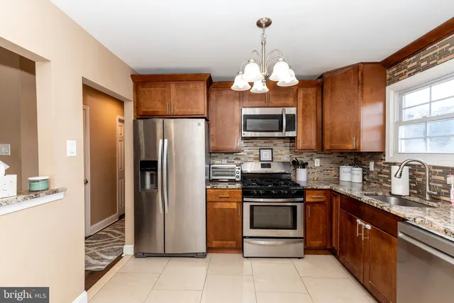 a kitchen with stainless steel appliances granite countertop a refrigerator a stove a sink a oven with a dining table and chairs