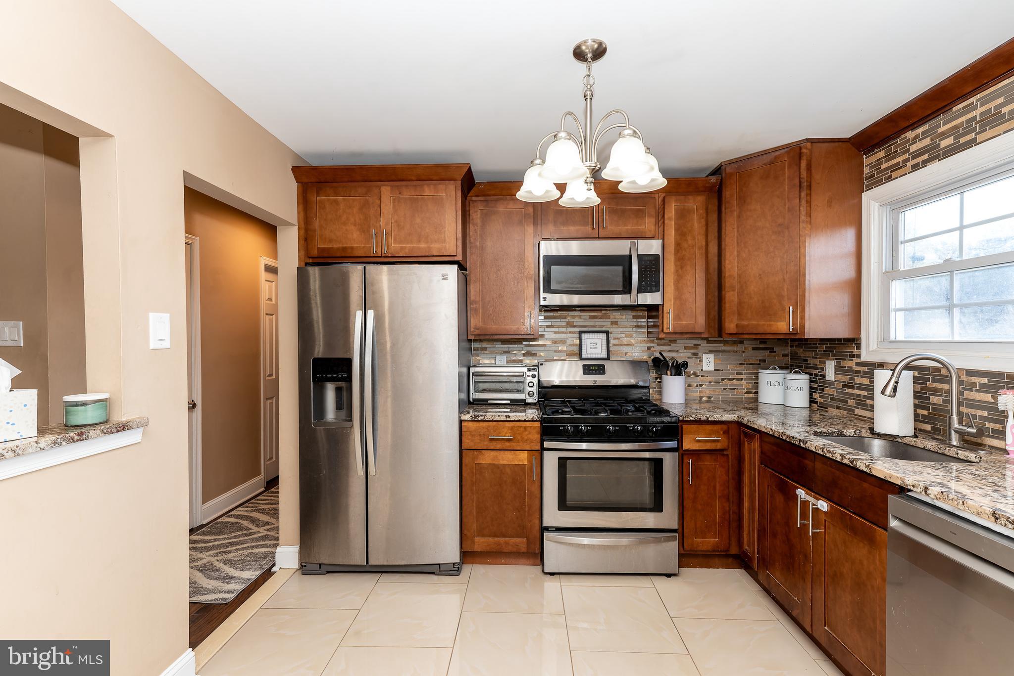 1207 Turnersville Road Pine Hill, NJ 08021 - Photo 9 of 31 a kitchen with stainless steel appliances granite countertop a refrigerator a stove a sink a oven with a dining table and chairs