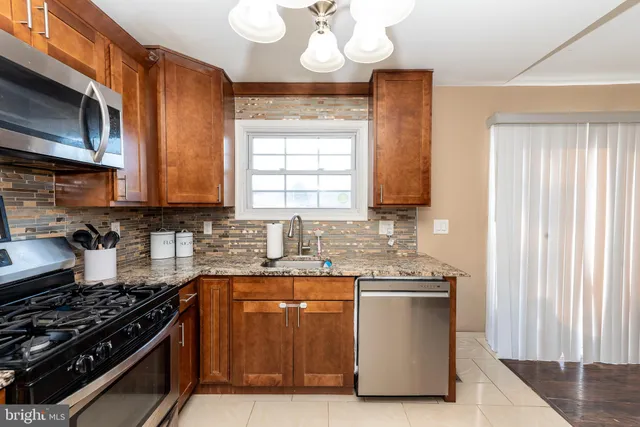 a kitchen with stainless steel appliances granite countertop a stove a sink and a microwave